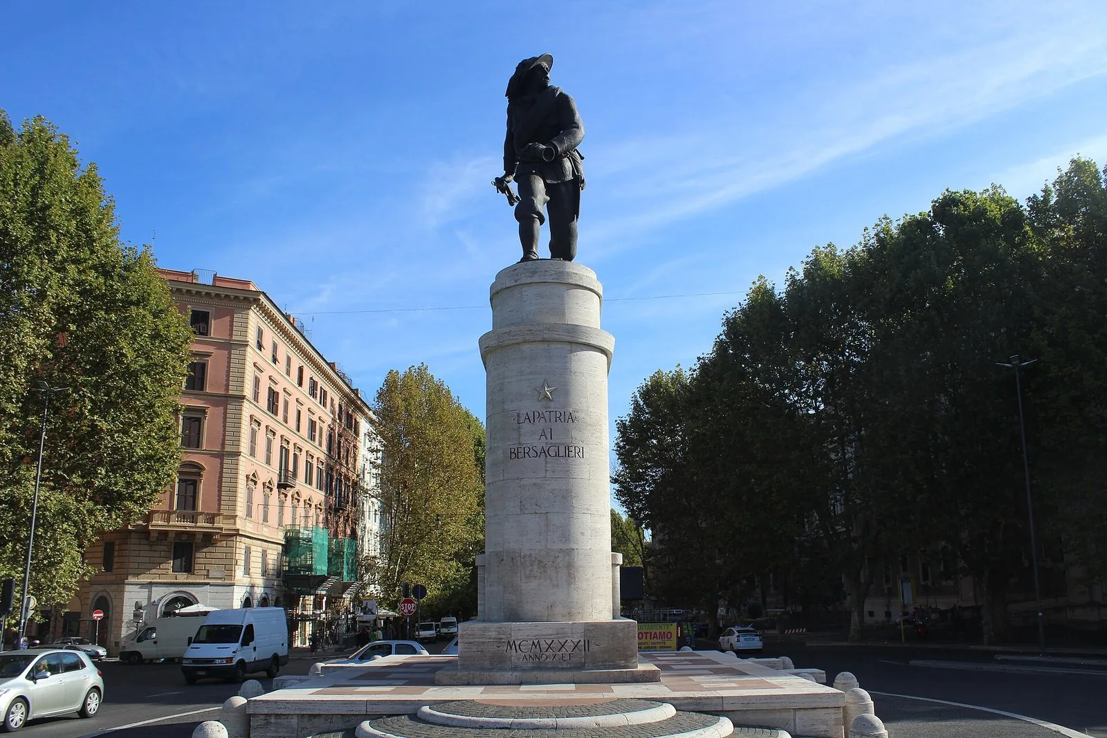 Un tratto alberato della Via Nomentana a Roma, con un monumento al centro della carreggiata
